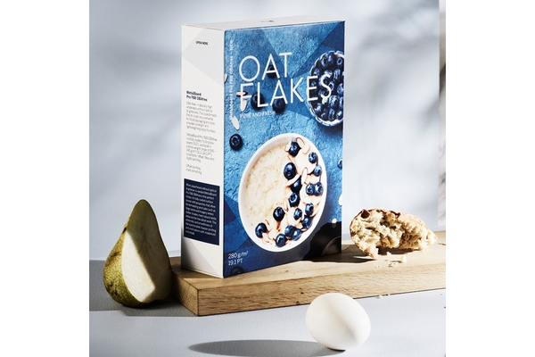 A box of oat flakes, an egg, and blueberries on a table.
